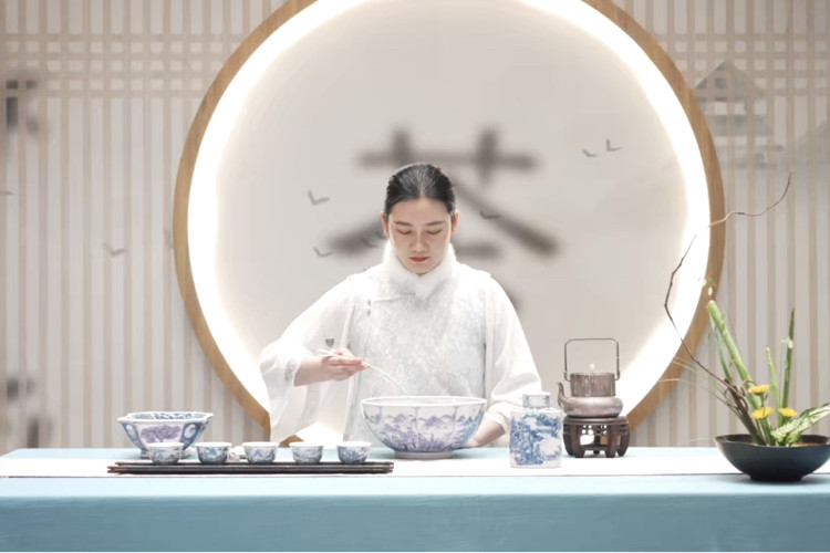 Woman in white traditional dress performing Chinese tea ceremony with porcelain